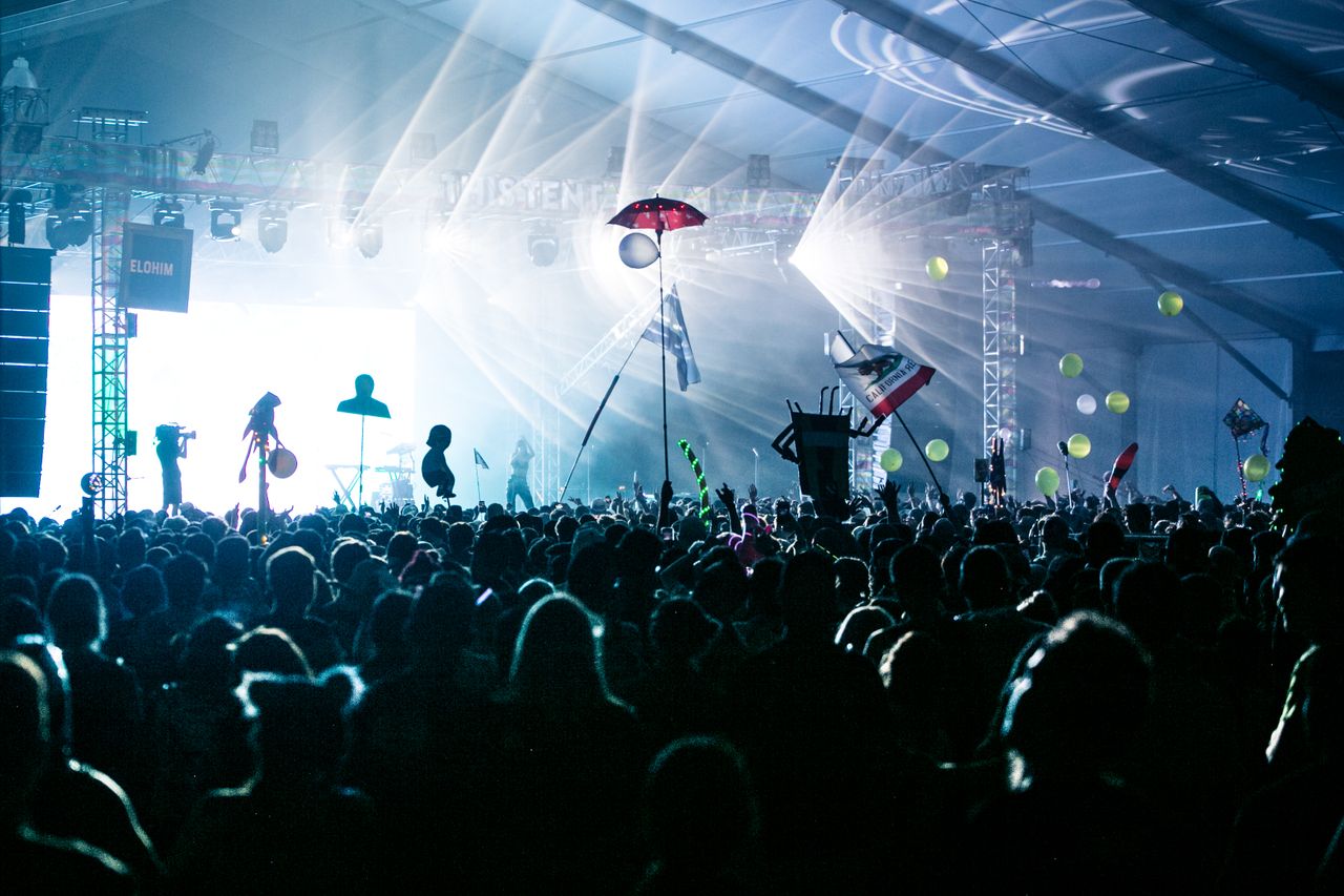 Concert crowd with hands raised under stage lights